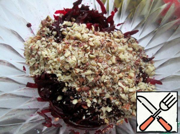 Wash the cranberries. Grate beets and nuts on a coarse grater, combine, season with salt, pepper, sour cream and cranberries, mix. Put in the refrigerator to cool.