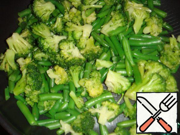 Disassemble the broccoli into small inflorescences. Put together with the string beans in a frying pan and pour in a little water (if the vegetables are thawed, then there is enough liquid in them and you can not add water).
