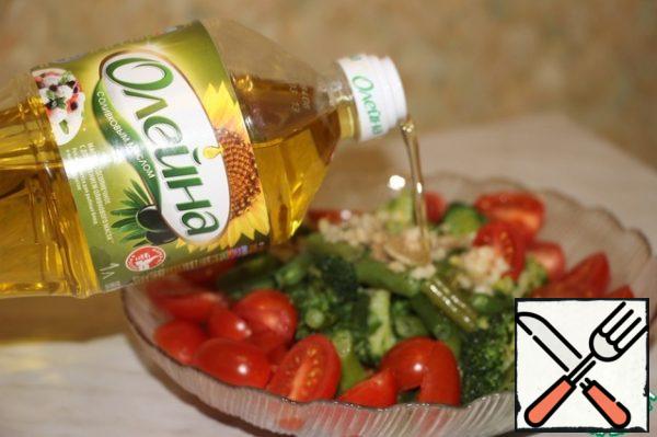 Now put all the ingredients in a salad bowl. Pass the garlic through the press, cut the onion into half rings, and cut the tomatoes in half. Drizzle with olive oil.
