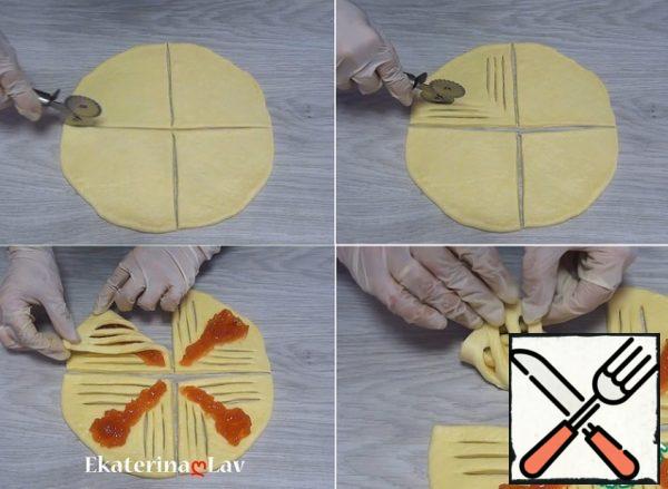 The circle is cut into 4 parts. On each sector, make 3 parallel incisions on both sides. Between the incisions in the center, I maintain a distance of one and a half to two centimeters. Distribute the filling in the center. I wrap one edge (I try not to stick the strips together), cover with the second one.
