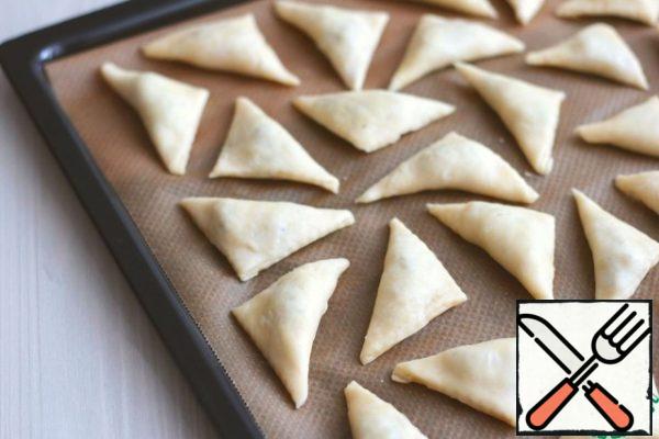 Place the triangles on a baking sheet covered with baking paper and send them to a preheated 180-190C oven for baking. Bake the triangles until golden brown.
