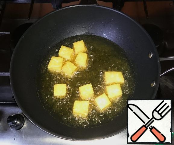 In the wok, heat the oil and fry the pieces of tofu in it. Add salt, but without enthusiasm. Fry in parts so that the oil does not cool, 7-10 minutes until Golden brown.