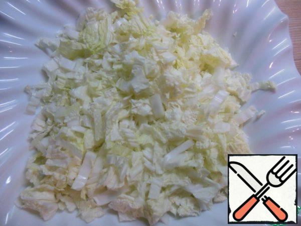 We cut the Peking cabbage into small pieces and put it on the bottom of our salad bowl, add a little salt and sprinkle with olive oil.
