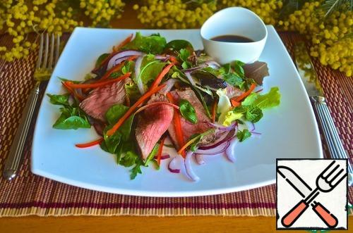 Put the lettuce and greens on plates, add the meat plates, pepper and red onion and pour the dressing. Serve immediately.