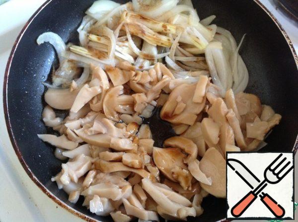 With mushrooms drain off any excess liquid and add to the onions. Pour in the soy sauce and fry the mushrooms with the onions.