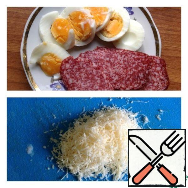 Eggs cut into rings, sausage thin slices. Grate cheese on a fine grater.