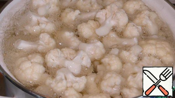 Wash the cauliflower, disassemble it into inflorescences.
Salt 1 liter of water to taste and bring to a boil. Put the cabbage in boiling water and cook for 3-5 minutes. We throw the cabbage on a sieve and let the water drain.
