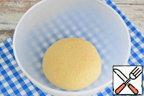 Mix liquid and dry ingredients, knead the dough.
The dough should be soft, plastic, quite dense, but not tight. It holds its shape well and does not stick to your hands and to the work surface.
Put the dough in a bowl, tighten with cling film and remove the bowl to heat for 50-55 minutes.