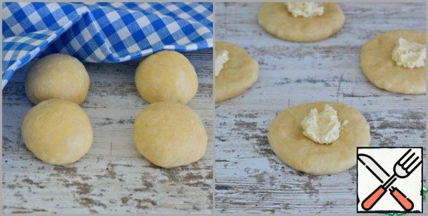 The second part of the dough (white) knead, divide into four equal parts. Roll out each blank into a flat cake, put 1/2 teaspoon of butter-vanilla filling in the middle of the flat cake. Dazzle the edges of the cake, forming a round bun.