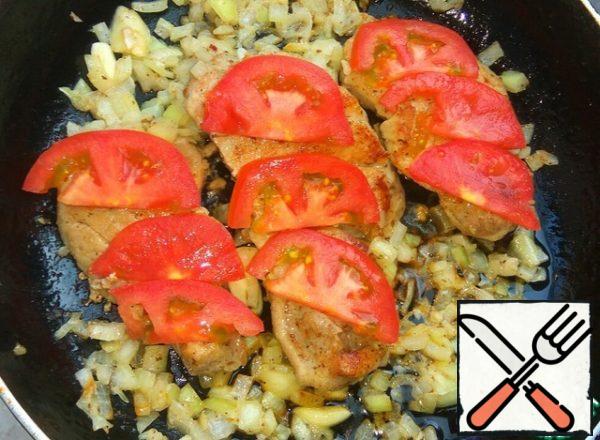 To the meat add the garlic and onion from the marinade. On the meat put the chopped tomato. Cover with a lid, fry for another 5 minutes.