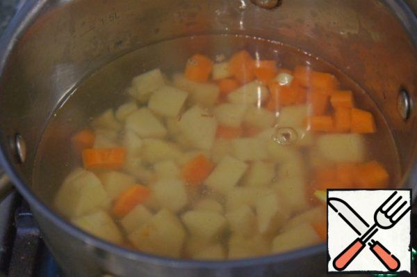 In boiling water, pour the potatoes and carrots, bring to a boil and cook over low heat for 5 minutes.
