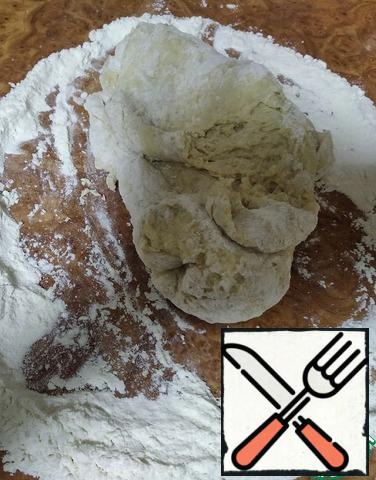 The remaining half a glass of flour pour on the table. Spread the dough and continue kneading.