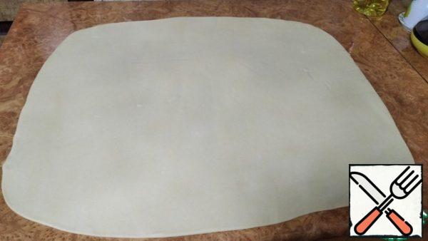 While we were engaged in stuffing and pillow our dough rested and became very pliable and elastic! Lubricate the table is not a large amount of vegetable oil and roll the dough into a rectangular layer 2 mm thick.
