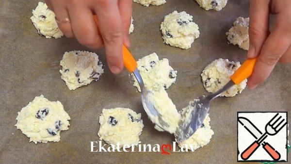 With two spoons spread small mounds of dough on a baking sheet, covered with parchment.