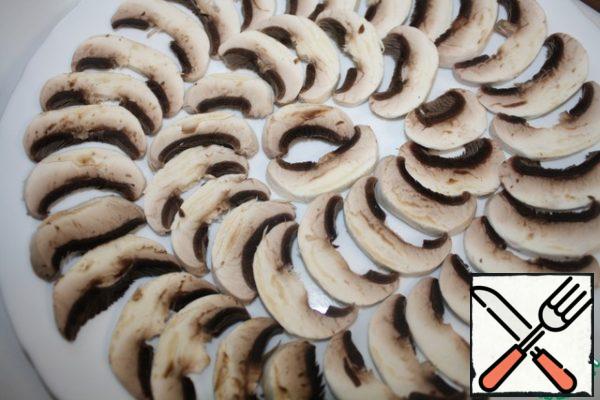 Slice thinly the mushrooms and arrange in one layer on a dish.