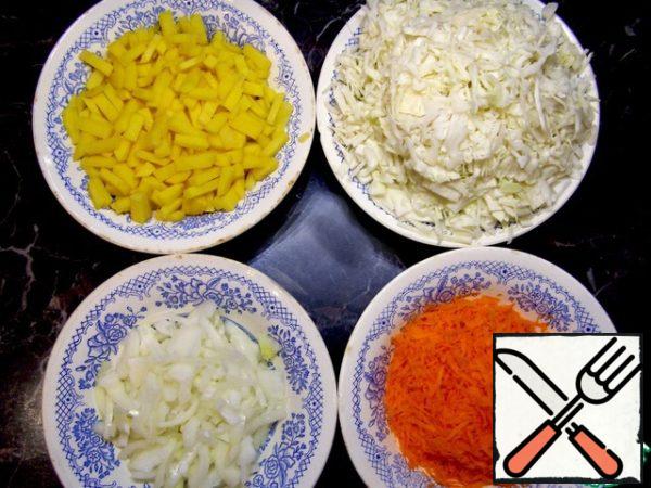 Prepare the vegetables: chop the cabbage, cut the onions and potatoes, grate the carrots.