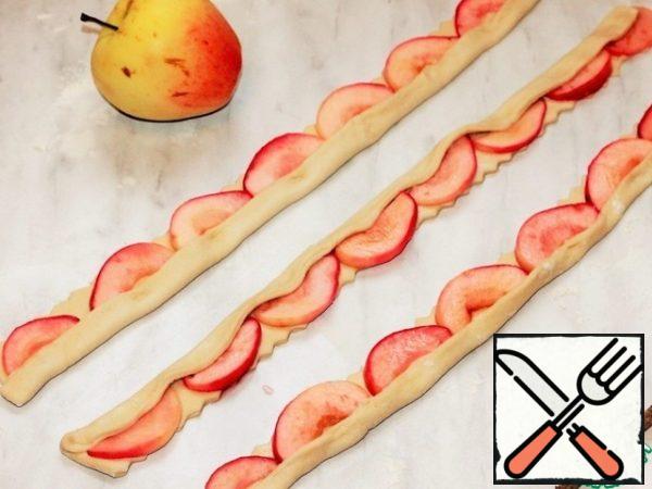 Put the Apple slices on the strips, close the edge of the strip with the dough and form the roses.