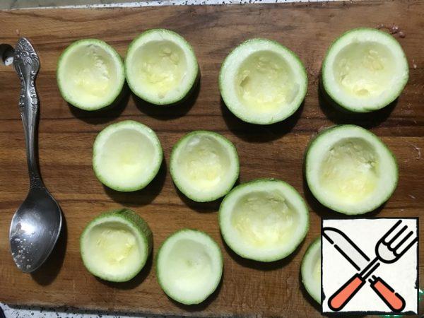 Wash zucchini, cut into barrels 5-7 cm wide. If young zucchini, it is better to make thicker. Spoon out the flesh, leaving the sides and bottom 0.5 cm. Salt.