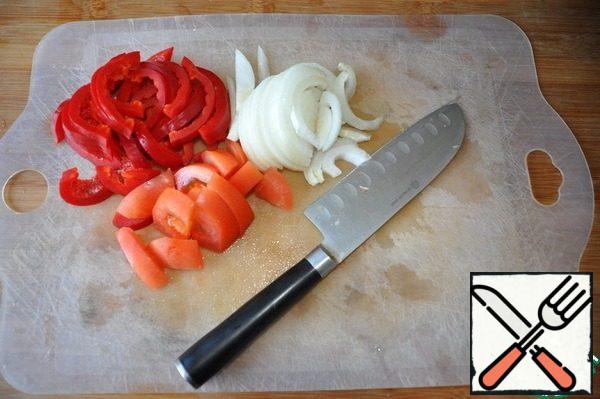All the vegetables are immediately washed, cleaned and cut, because the dish is prepared quickly. Pepper and onion cut into thin strips, tomato quarters.