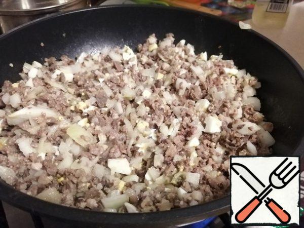 Next, add finely chopped eggs and chopped onion to our filling. Mix everything well and send it to bake in a deep frying pan. In my case, a wok was used. Fry until the onion is ready, stirring the contents of the wok more often.
