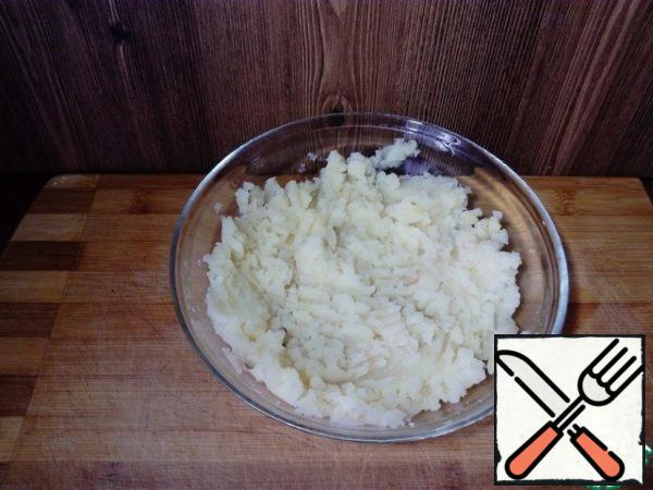 Boil the potatoes in their skins. Cool, clean and with a fork turn into a homogeneous mass.