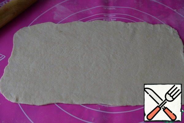 Take out the dough from the refrigerator, divide in half.
The Mat is covered with flour if necessary, roll out the dough into a rectangular layer 3 mm thick.
