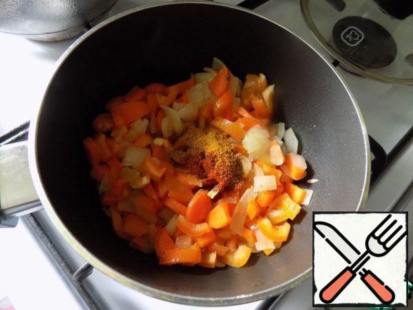 Fry the onion and add the carrots, chopped finely and arbitrarily. After about five minutes, put the pepper, also finely chopped it. Turn down the heat, cover and simmer for 5 minutes. Lay out the spices, mix.
