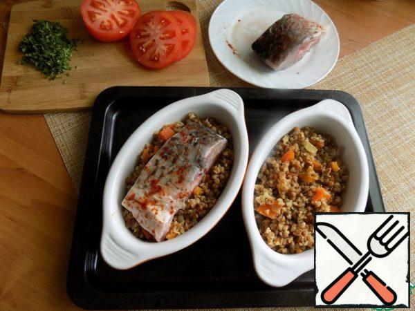 I will serve the dish in portions. After greasing the molds with oil, put a layer of buckwheat on the bottom. Fish on top. Put a slice of tomato on the fish. From above, the fish and tomatoes are watered with oil quite a bit, everything is beautifully fried.
