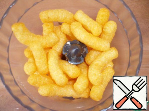 Put the cheese-flavored corn sticks in a food processor and chop.
