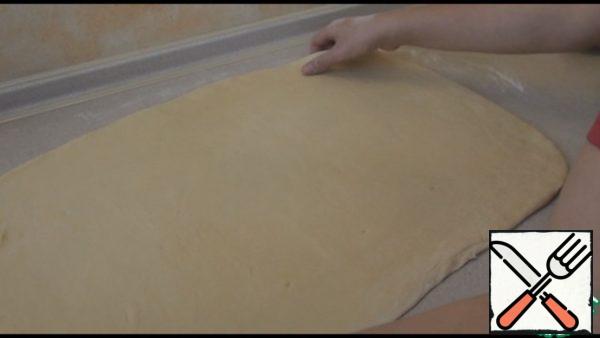 When the dough rises, take it out, obomnem and roll out into a rectangular layer, about 5 mm thick. Then we need to divide this layer into about 4 parts. I did it with a ruler, marking my finger on the division dough.