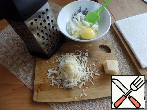 Grate the hard cheese on a medium grater. In cottage cheese, break the egg, add 2/3 of the hard grated cheese and connect everything. 1/3 of the hard cheese is left for sprinkling the tart before baking.