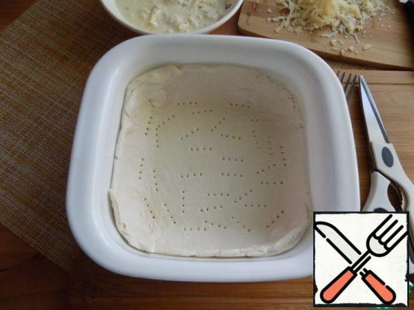 Spread the dough in the form, forming the sides. With a fork, the bottom of the dough is pricked. (See photo)