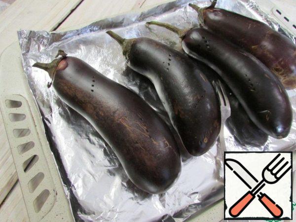 Eggplant prick with a fork in several places. Cover the baking sheet with foil. Put the eggplant on it. Send a baking sheet for 55 minutes in a preheated 180 degree oven. The eggplant should be very soft.