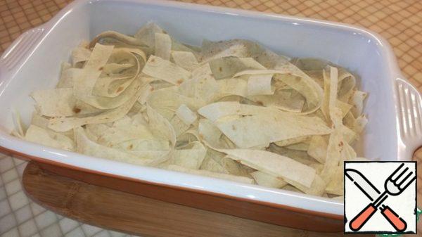 In a baking dish, I have it 28×18, spread the first layer of chopped pita bread.