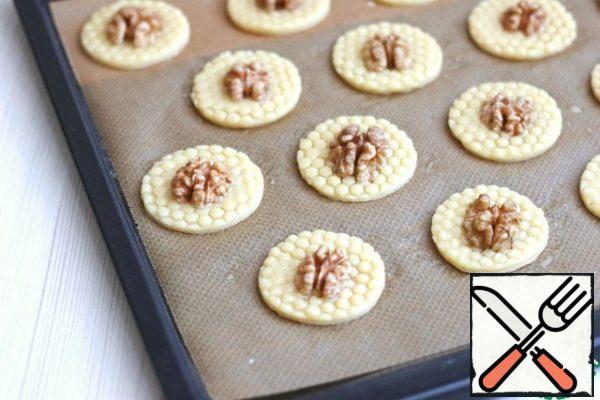Place the cookies on a baking sheet covered with baking paper, brush with beaten egg, add the walnut kernels in the middle and send them to the oven preheated to 170-180C.
