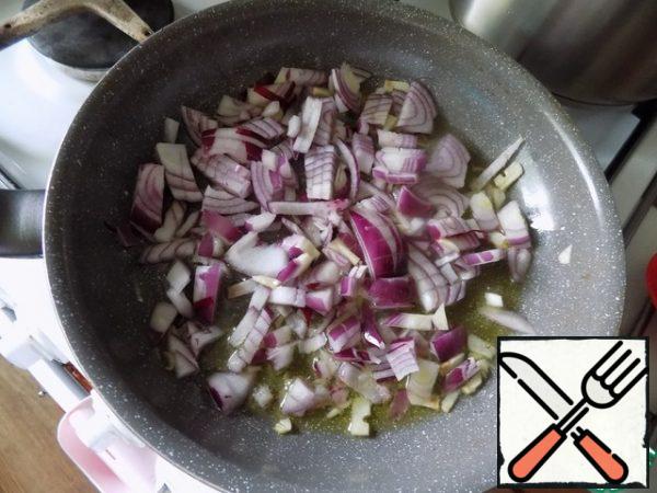 Prepare vegetables for a "pillow" for cabbage rolls. Pour oil into a frying pan, heat it up. We spread the finely chopped garlic, after a minute - the onion, cut arbitrarily. Fry a little until soft.
