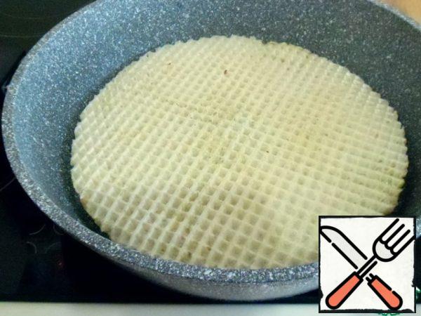 Now that the cakes are prepared, cover with a frying pan. With the help of a padded Board, tip the workpiece to the bottom of the pan.
Fry on low heat, in a dry pan.
When the bottom is browned, using the same Board or flat cover, flip and fry the second side.