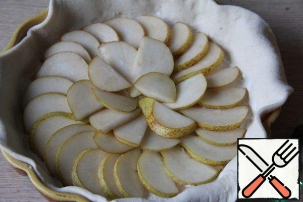 Defrost puff pastry (if using ready-made), roll out the shape (the diameter of the dough-24 cm) and line the bottom.
Pears wash, remove the core and cut into thin plates. Lay out on the entire form.
