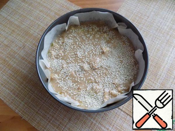 Preheat the oven to t-180 C. For baking, I will use a detachable ring D-20 cm. I'll cover it with baking paper. The paper is not oiled, and I smeared it with a small amount of oil. Lay out the dough and spread evenly. Sprinkle white sesame seeds generously on top. You can sprinkle with seeds or chopped nuts. Put it in the oven, setting the time for 30 minutes.
