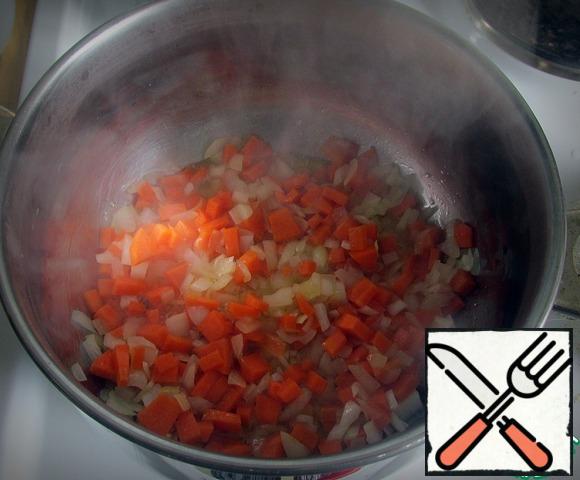 In a saucepan with a thick bottom over medium heat, heat the vegetable oil. Add the onions and carrots, fry, stirring, 4-5 minutes.
