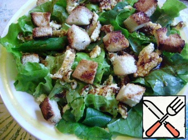 On the salad spread the croutons and pour the dressing.