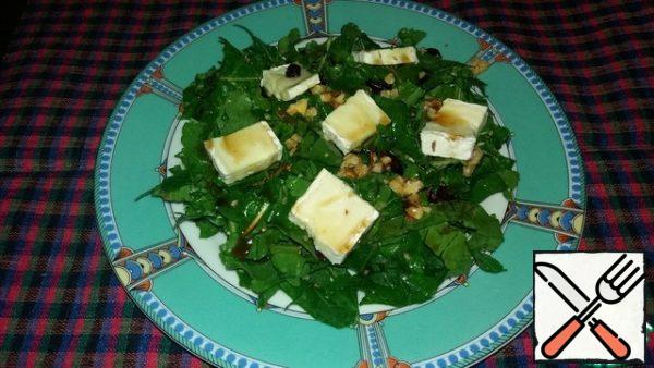 The basis of the salad spread on plates, put the pieces of cheese on top and pour the sauce.