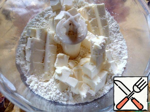 Add the cold butter, cut into small cubes, turn on the blender again and mix the ingredients until fine crumbs.