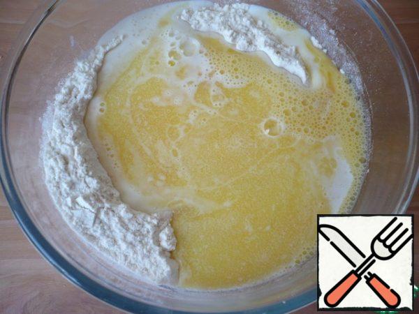 In the flour mixture, make a deepening pour warm milk, melted butter and beaten egg.