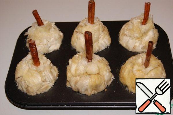 Put it in a mold, brush with butter and sprinkle with sugar. Secure the edges by piercing with a cinnamon stick.
