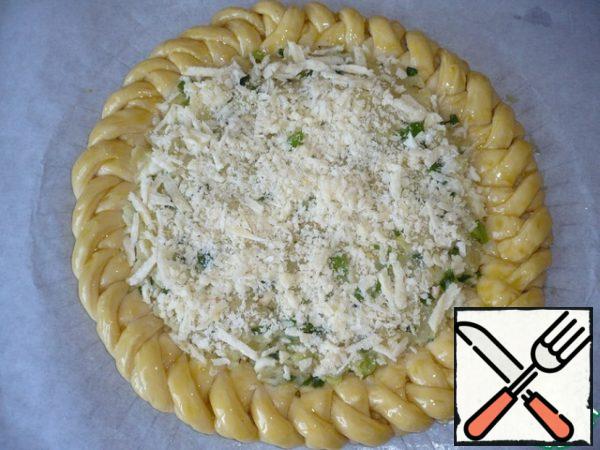 The braided part of the pie to lubricate the yolk. Grate Parmesan cheese on a coarse grater and sprinkle it on top of the filling. With the help of parchment, transfer the pie to a baking sheet.