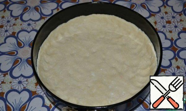 The cream should not be completely cold. We need it warm, not completely cooled down.
Next: grease the baking dish well with vegetable oil, lay out a ball of dough, knead a hand-sized mold and do not have high sides, about 1.5 cm in size.
It is better to take a split form, with a diameter of 24 cm.
