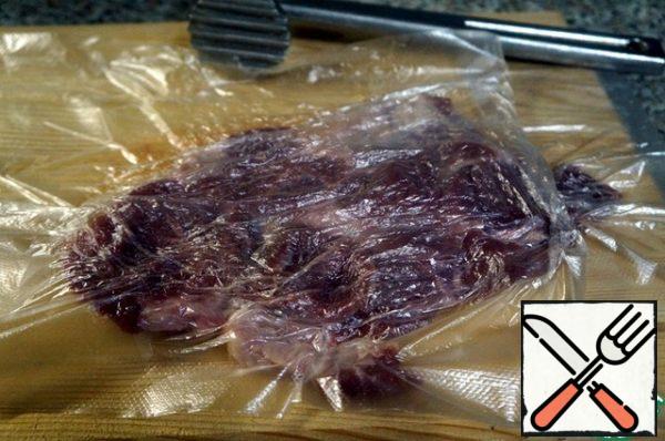 Cover the meat with a film, beat it well with a hammer.
