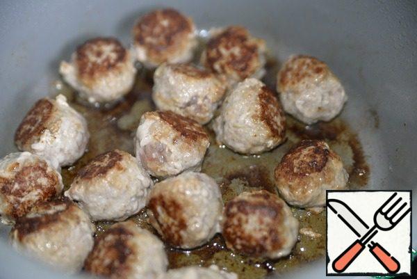 Take a cauldron or pan, a frying pan with a thick bottom, heat, pour oil and fry the meatballs on all sides until Golden on a high heat. Remove the meatballs on a plate.