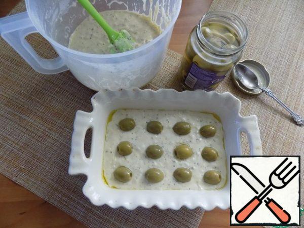 Spread half of the dough in the form and put on top of the olives as much as fit.